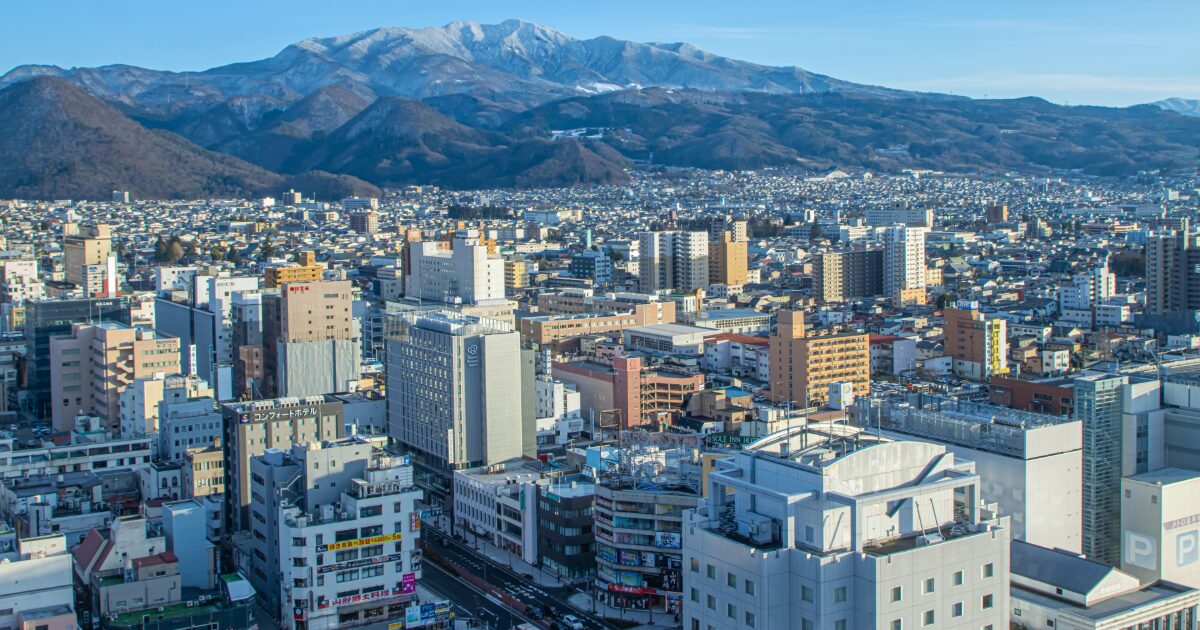 雪をかぶった山々と山形市中心部のパノラマ