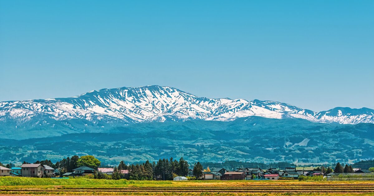 雪をかぶった月山と里の風景